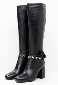 Czarne kozaki sięgające do kolan, wykonane z gładkiej skóry, z masywnym obcasem, zdobione łańcuchem z kwiatowym akcentem oraz bocznym zamkiem.