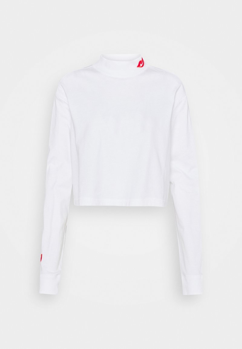 White cropped long-sleeve turtleneck made of cotton. Features a small red flame logo on the collar and red accents on the sleeve cuffs.