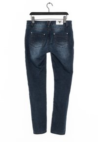 Mörkblå denimjeans med smal passform, fem fickor, subtil blekning och metalldetaljer i silverton. Hängande på en svart metallgalge.