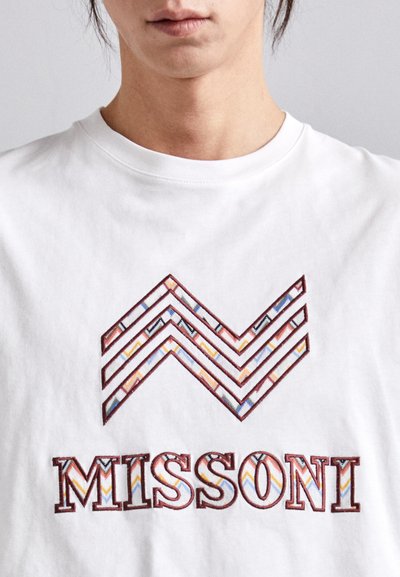 T-shirt en coton blanc avec broderie zigzag multicolore et "MISSONI" en lettres épaisses et colorées sur la poitrine.