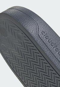 Ciemnoszara podeszwa o fakturowanej powierzchni, z wzorem w jodełkę oraz detalem z logo. Wykonana z materiału przypominającego gumę, co zapewnia przyczepność i trwałość.