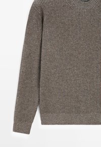 Maglione marrone a coste con maniche lunghe, texture in maglia e scollo a girocollo. Sfumature di colore sottili aumentano la profondità visiva complessiva.