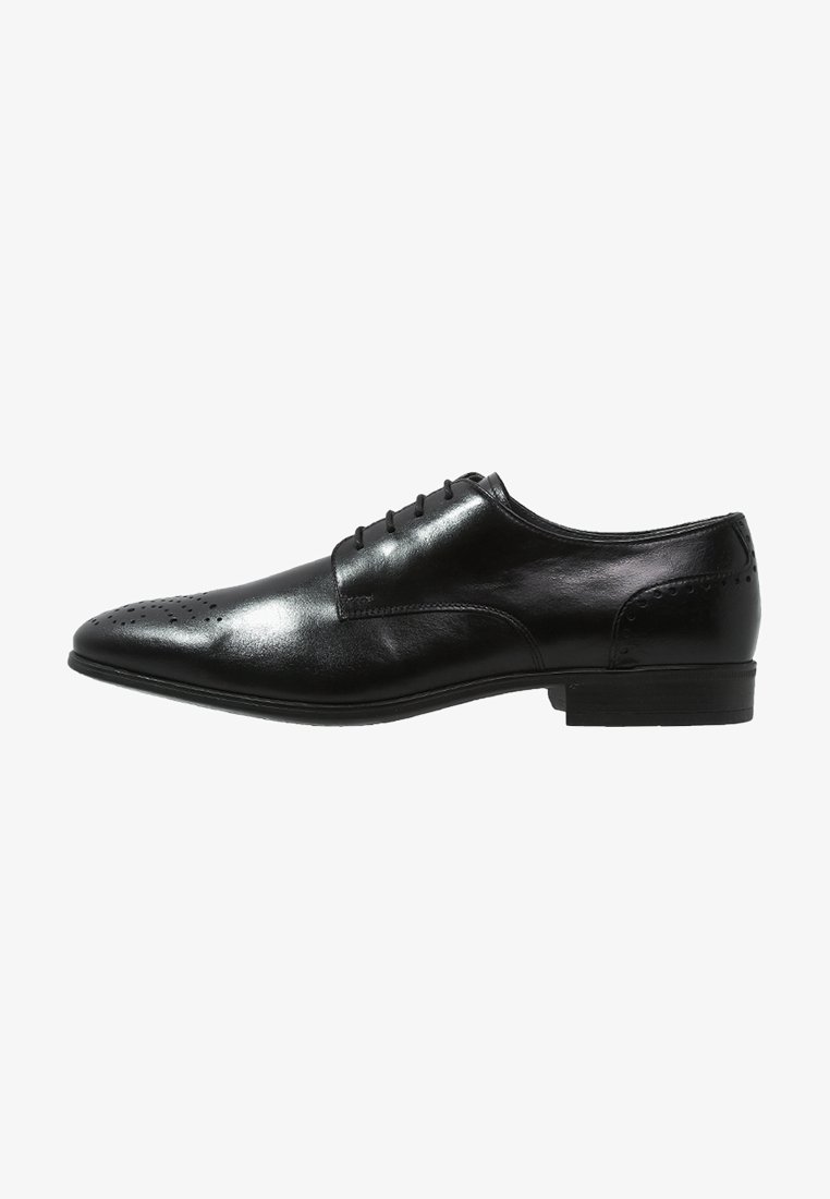 Chaussure Oxford formelle en cuir noir avec laçage fermé, bout perforé et petit talon, présentée en profil latéral face gauche.