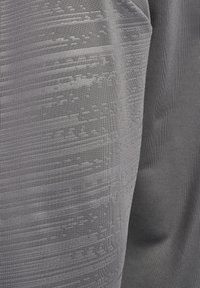 Grijze sportstof met een gestructureerd patroon, bestaande uit horizontale en verticale ontwerpen, een gladde afwerking en een iets glanzende uitstraling.