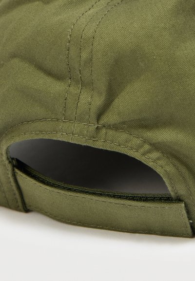 Καπέλο σε ελιά πράσινο με καμπυλωτό γείσο, κατασκευασμένο από ανθεκτικό ύφασμα. Διαθέτει ραμμένες λεπτομέρειες και ρυθμιζόμενο ιμάντα στο πίσω μέρος.