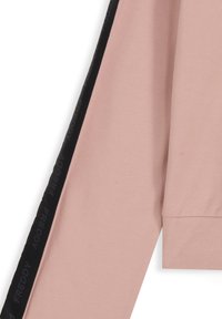 Top de manga larga rosa, hecho de tela suave, con una franja lateral negra con la marca 'FREDDY' y un corte relajado con mangas puñadas.