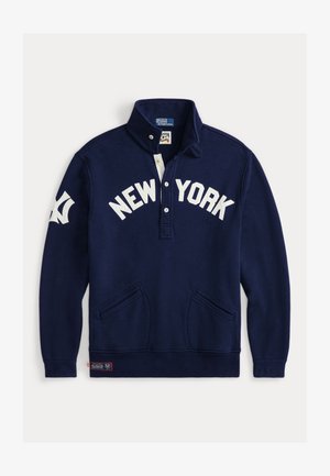 Sudadera tipo pullover de color azul marino con cuello alto, letras blancas "NEW YORK" y dos bolsillos frontales. Presenta un pequeño parche de logo en el dobladillo.