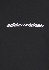 Black cotton t-shirt featuring "adidas originals" logo in white, centrally placed, with a smooth, textured fabric finish.