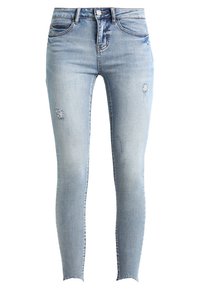 Jeans ajustados en denim de color azul claro con detalles desgastados. Cuenta con cinco bolsillos y una cierre de botón. Los dobladillos deshilachados añaden un acabado texturizado.