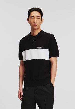 Zwart-wit korte mouwen polo shirt met een horizontale witte streep, geribde kraag en een drie-knopen blk. Logo op de borst.