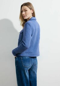 Blauwe wolmix jas met een kraag, een voorzak, een gestructureerde afwerking en een cropped design, gecombineerd met donkerblauwe denim jeans.
