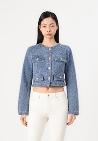 Blauwe tweed cropped jasje met lange mouwen, ronde halslijn, vier voorkiezen en zilveren knoopsluitingen. Getextureerde stof met variërende tinten.