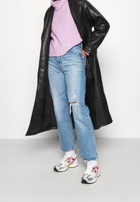 Zwarte leren jas, lila ribbel turtleneck, gescheurde lichtblauwe jeans en multicolore sneakers met zilveren en neonaccenten.