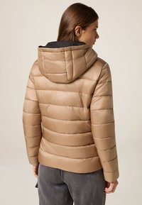 Beżowa kurtka puchowa z kapturem, z poziomymi przeszyciami, błyszcząca w fakturze, z czarnym wnętrzem. Dopasowana w talii, z długimi rękawami.