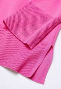 Rosa Pullover mit gerippter Textur. Verfügt über umgeschlagene Ärmelbündchen und einen seitlichen Schlitz, der eine glatte Strickstruktur und eine lebendige Farbe hervorhebt.