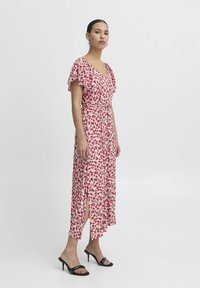 Floral maxi dress with a V-neck, short ruffled sleeves, and side slits. Fabric features a pink and green flower pattern on a light background.