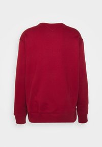 Langärmeliges, einfarbig rotes Sweatshirt mit Rundhalsausschnitt, gerippten Bündchen und Saum, von hinten vor hellem, einfarbigem Hintergrund gezeigt.