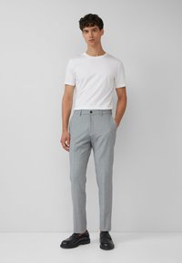 Heren grijze pantalon met een slim fit, textuurstof, enkel knoopsluiting en twee zijzakken. Gecombineerd met een plain wit T-shirt.