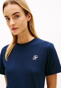 Μπλε βαμβακερό t-shirt με στρογγυλή κορυφή, διαθέτει λευκό κεντημένο λογότυπο στην αριστερή πλευρά του στήθους. Μαλακή υφή και κλασικός σχεδιασμός.