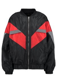 Giacca bomber nera con design a blocchi di colore triangolari rossi e grigi, zip frontale, polsini ed orlo elasticizzati, e materiale morbido e lucido.