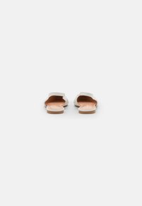 Weiße Slide-Sandalen mit strukturiertem Obermaterial, offenem Zehendesign und flacher beiger Sohle. Minimalistischer Stil ohne sichtbare Verzierungen.