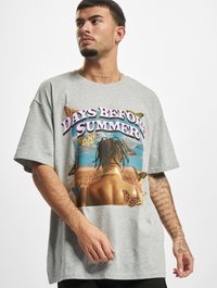 Camiseta de algodón gris de manga corta, con un colorido estampado gráfico de una persona con mariposas sobre un fondo escénico.