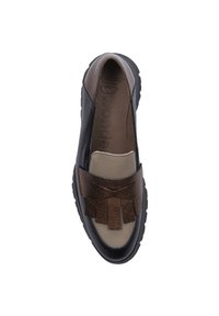 Zapato negro y marrón tipo slip-on con un upper texturizado, que presenta un fleco de cuero decorativo y una puntera redondeada. Suela de goma de perfil bajo.