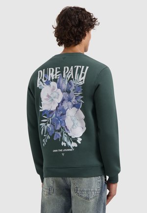 Groene sweatshirt met ronde hals, voorzien van een bloemenprint in blauw- en wittinten op de achterkant met de tekst "PURE PATH" erboven en "OWN THE JOURNEY" eronder.