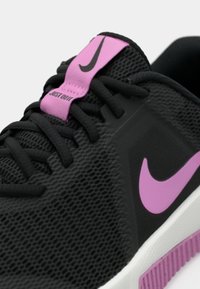 Melnas kedas ar sieta augšdaļa, roze krāsas akcenti uz mēles un zīmola simbolu, fakturēta zole ar purpura detaļām un melnām šņorēm.