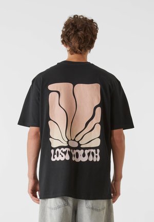 Svart bomullströja med en stor abstrakt grafik på baksidan i ljusrosa, som visar "LOST YOUTH" i ett lekfullt typsnitt.