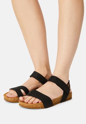 Sandalias de cuero negro con suelas de corcho, que cuentan con dos correas anchas y un diseño con bucle para el dedo del pie. Correas ajustables en el tobillo para un ajuste seguro.