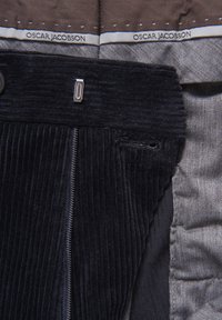 Laivastonsininen samettikangas vetoketjulla, jossa on hopeinen metalliyksityiskohta, yhdistettynä kontrastiseen sileään harmaaseen vuoriin.