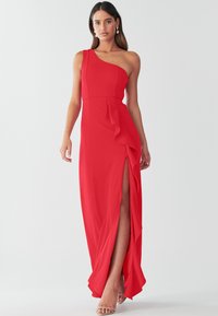 Vestido maxi rojo con diseño de un solo hombro, escote asimétrico, detalles de volantes en capas y una abertura alta en el muslo para mayor detalle.