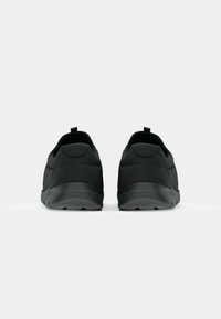 Black athletic shoes with a smooth texture, rounded shape, and a subtle diamond pattern on the upper. Features a back pull tab and rubber sole.
