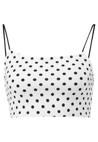 Vit crop top med svarta prickar, med tunna svarta remmar och en mjuk textur. Designad för vardagsbruk, strukturerad utan knäppning.