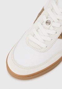 Valge toss, millel on tekstureeritud tan-tooniline paneel, pehmed seemisnahast aktsendid, lamedad paelad ja kergelt pruunika tooniga kummist tallad.