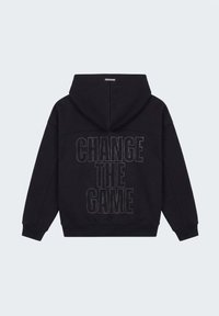 Sweat à capuche noir à manches longues avec la phrase « CHANGE THE GAME » en contour pointillé au dos.