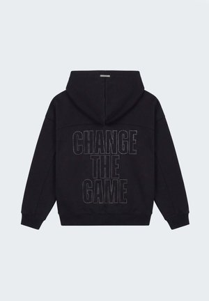 Sudadera negra con capucha y mangas largas, con la frase "CAMBIA EL JUEGO" en contorno punteado en la parte trasera.