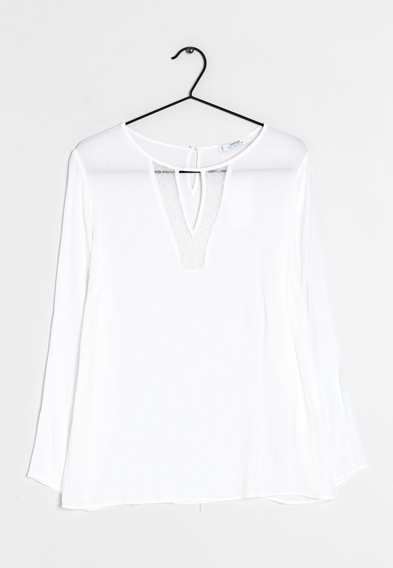 Valkoinen pitkähiha blouse syvällä V-kaula-aukolla, joka on varustettu pitsiyksityiskohdalla. Pehmeä, kevyt kangas, jossa on löysä istuvuus ja kaareva helma. Roikkuu mustassa koukussa.