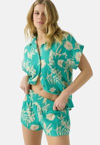 Chemise à manches courtes turquoise avec boutons et short smocké assorti à motif floral en crème, offrant une coupe décontractée et une texture douce.