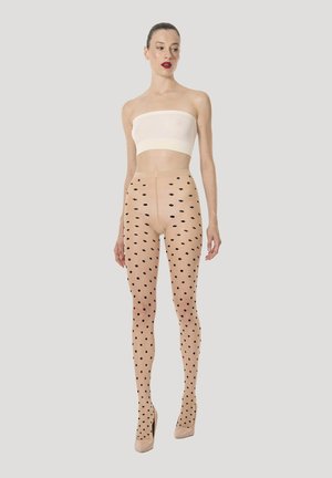 Collant trasparenti color nudo con motivo a pois neri, caratterizzati da una vita alta e una banda opaca. La modella li abbina a un top senza spalline e tacchi.