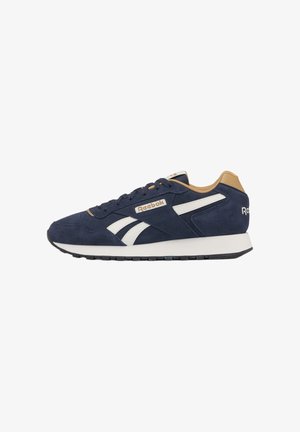 Sneaker Reebok blu navy e marrone chiaro con strisce bianche laterali, design con lacci e suola nera, vista laterale.
