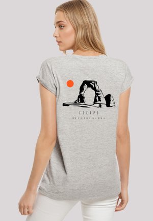 Graues T-Shirt mit aufgerollten Ärmeln, das ein schwarzes Motiv eines Bogens und eine orangefarbene Sonne auf dem Rücken zeigt. Leichter Stoff mit lässiger Passform.