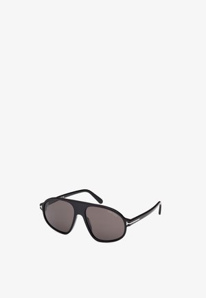 Gafas de sol negras con lentes oscuros, de forma aerodinámica y acentos de metal. Las monturas tienen un acabado mate y una marca sutil.