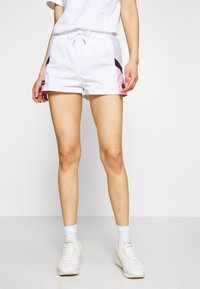 Shorts blancs avec des accents roses et noirs, une taille avec cordon de serrage et des poches sur les côtés. Le matériau semble léger et décontracté.