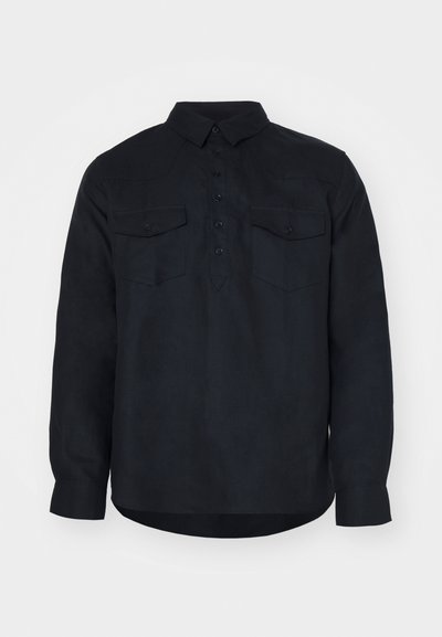 Camisa de manga longa azul-escuro, feita de um tecido texturado, com um fecho frontal abotinado, dois bolsos no peito e um colarinho clássico.