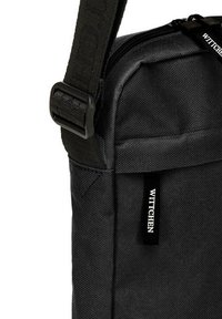 Borsa a tracolla in tessuto nero con una borsa resistente, dotata di chiusura zip, superficie texturizzata e un piccolo etichetta logo WITTCHEN.