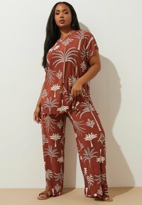 Set di tunica e pantaloni color ruggine con motivi di palme bianche. Leggero, vestibilità comoda con maniche corte e spacco laterale per maggiore comfort.