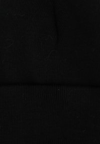 Berretto in maglia nera con texture a coste e risvolto. Il tessuto appare morbido con una leggera peluria, offrendo una vestibilità aderente.