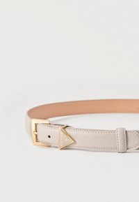 Ζώνη από δέρμα με υφή σε μπεζ χρώμα με χρυσή μεταλλική αγκράφα σε σχήμα τριγώνου που φέρει το λογότυπο "Guess" και ρυθμιζόμενο ιμάντα.